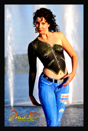 black haired woman body painted in a vest type top with a sleave on right arm in black with white highlights and detailed jeans